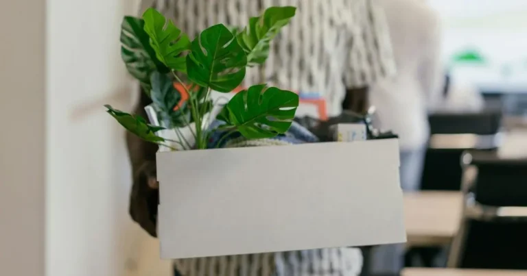 A project manager leaving his workplace with a box of belongings.