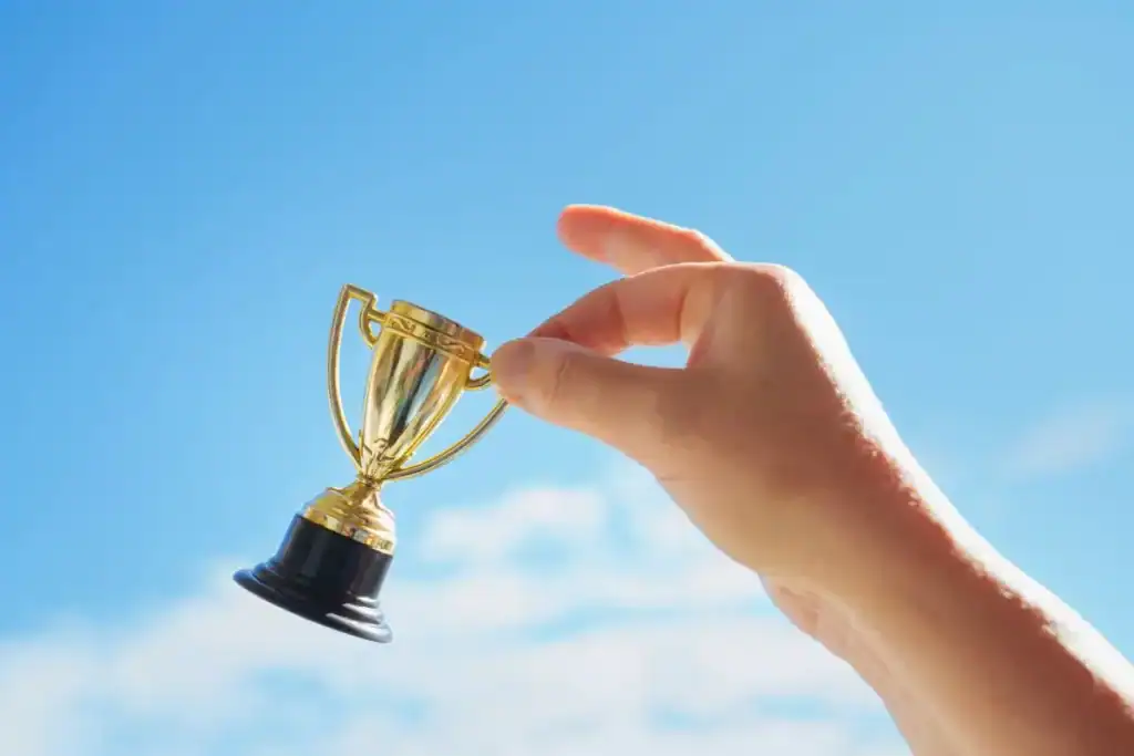 A hand holding a small trophy representing agile certifications