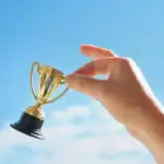 A hand holding a small trophy representing agile certifications